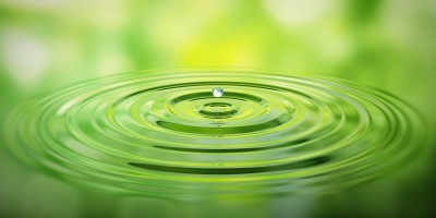 Wassertropfen auf Wasser mit grner Spiegelung